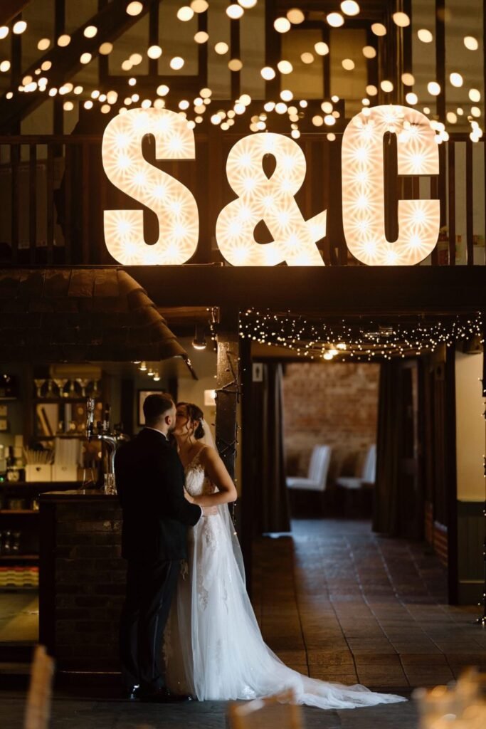 Couple in front of illuminated initials at Cooling Castle Barn