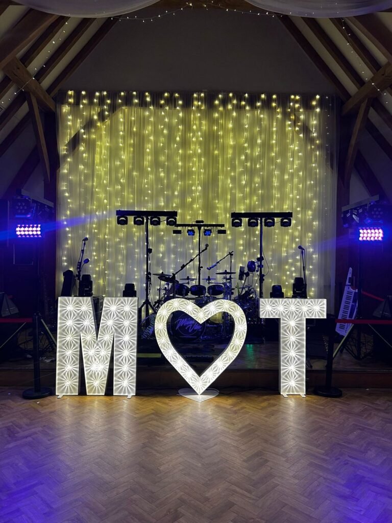 Illuminated initials and heart by the stage at The Old Kent Barn